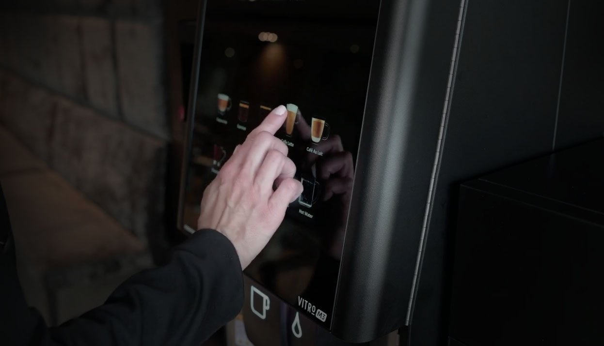 Persona utilizando una máquina de café automática durante una orientación de servicio